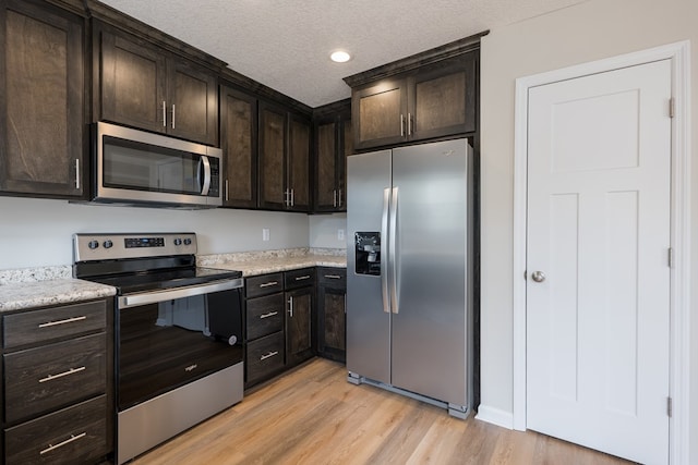 kitchen with light wood-style flooring, appliances with stainless steel finishes, a textured ceiling, dark brown cabinets, and recessed lighting