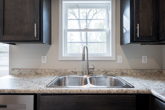 kitchen with light countertops, a sink, and dark brown cabinetry