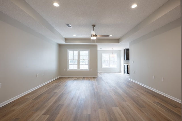 unfurnished living room with a ceiling fan, a textured ceiling, baseboards, and wood finished floors