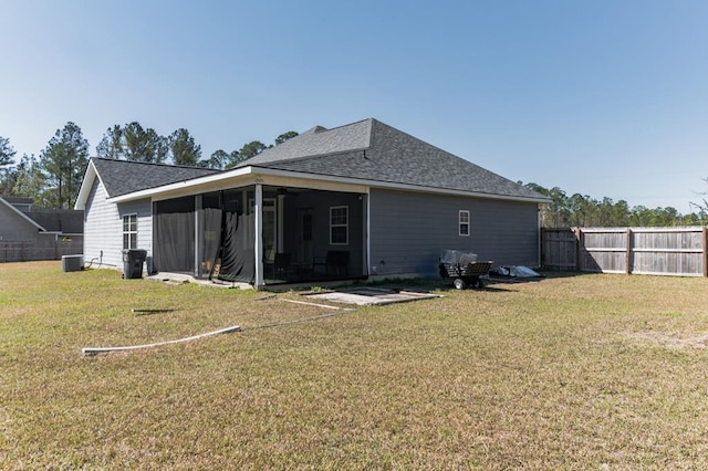 rear view of house featuring a yard, fence, a sunroom, and a shingled roof