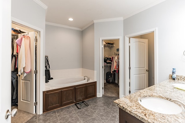 full bath featuring vanity, ornamental molding, a spacious closet, a garden tub, and tile patterned floors