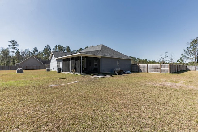 rear view of house featuring a lawn, a shingled roof, a fenced backyard, and a sunroom