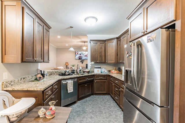 kitchen featuring crown molding, light stone counters, hanging light fixtures, stainless steel appliances, and a sink