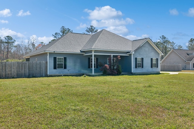 view of front of property with roof with shingles, a front lawn, and fence