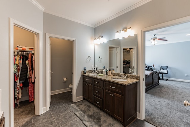 bathroom featuring double vanity, toilet, baseboards, and ornamental molding