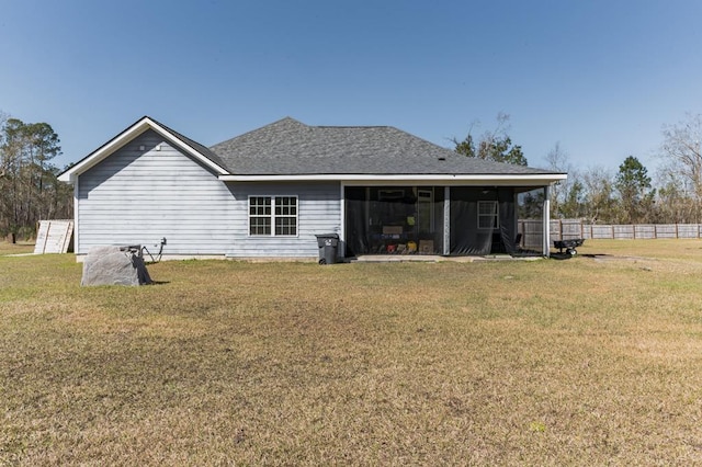 rear view of house with a yard, fence, and a shingled roof