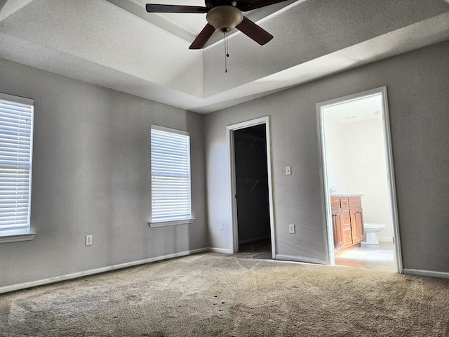 unfurnished room featuring a tray ceiling, ceiling fan, plenty of natural light, and light carpet