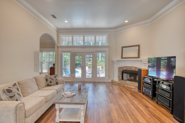 living area with a premium fireplace, arched walkways, ornamental molding, and a healthy amount of sunlight