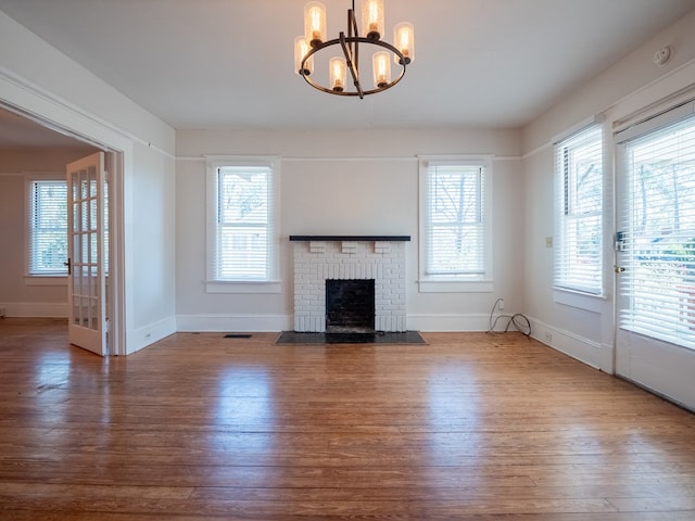 unfurnished living room with a wealth of natural light, a brick fireplace, baseboards, and wood finished floors