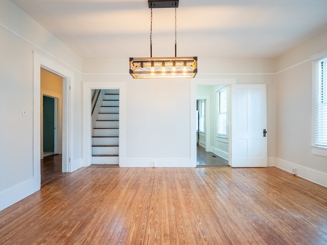 unfurnished room featuring stairway, wood finished floors, and baseboards