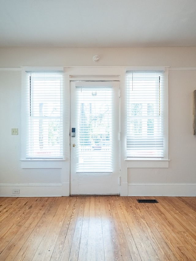 doorway to outside with visible vents, baseboards, and wood finished floors