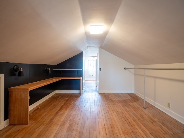 bonus room with vaulted ceiling, light wood-style flooring, and baseboards