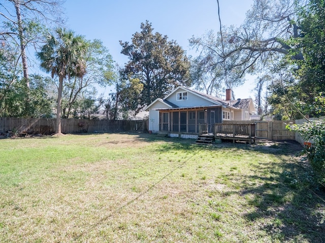 view of yard with a wooden deck, a fenced backyard, and a sunroom