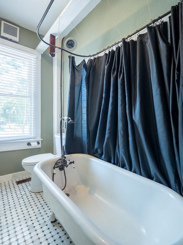 bathroom featuring toilet and a soaking tub