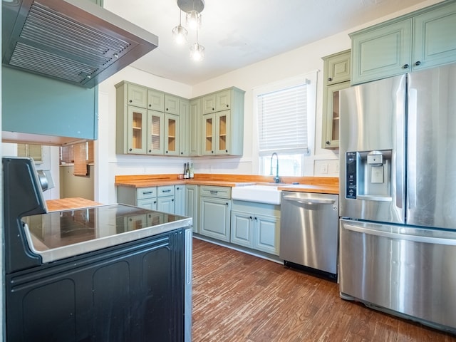 kitchen featuring glass insert cabinets, appliances with stainless steel finishes, dark wood-style flooring, extractor fan, and wooden counters