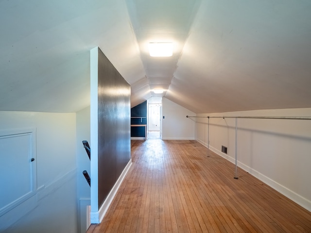 bonus room with lofted ceiling, visible vents, baseboards, and wood finished floors