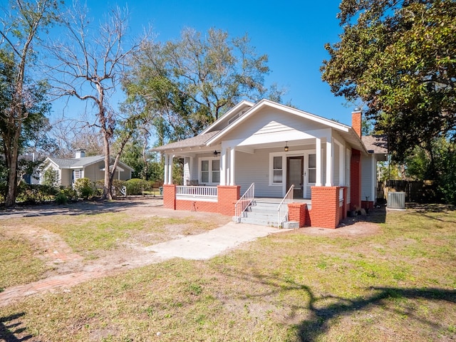 bungalow-style home with a chimney, a porch, and a front yard