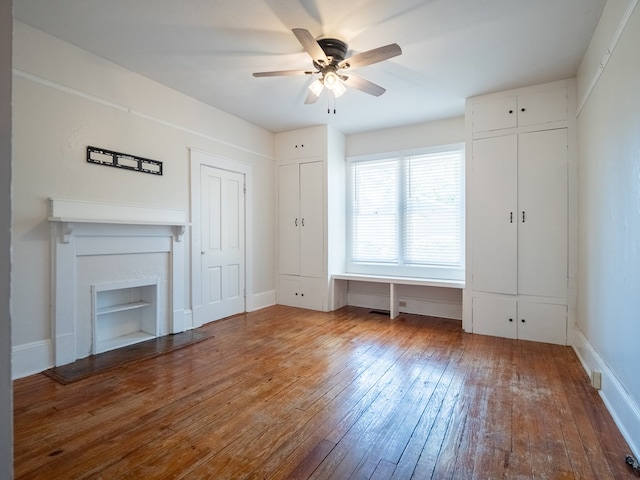 unfurnished bedroom featuring wood finished floors, a fireplace, baseboards, and two closets