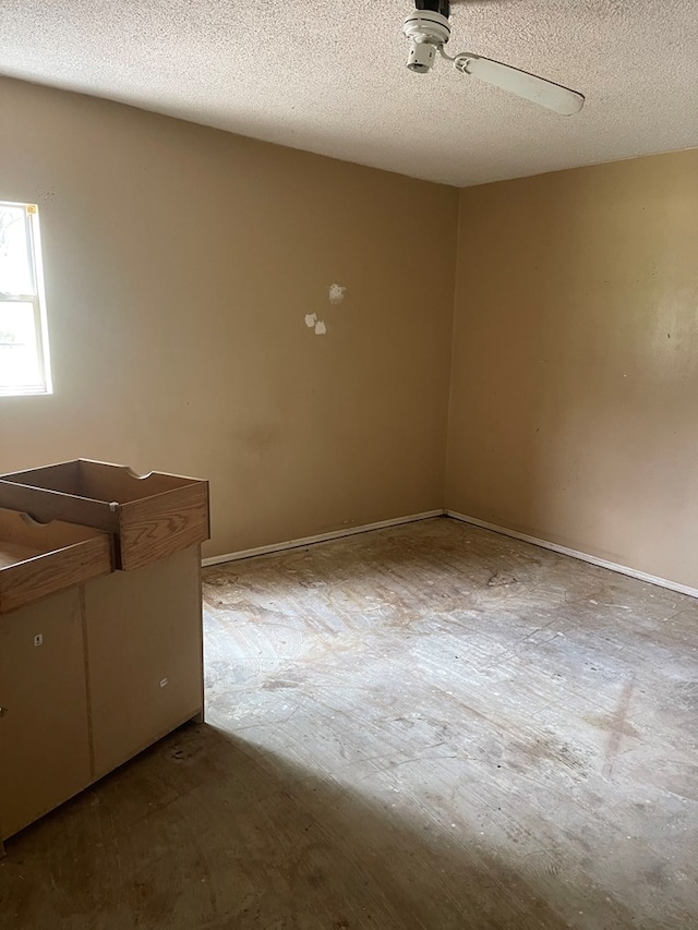 empty room with a ceiling fan and a textured ceiling