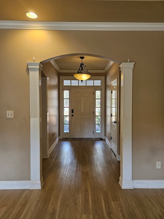 entrance foyer featuring dark hardwood / wood-style floors, ornate columns, and ornamental molding