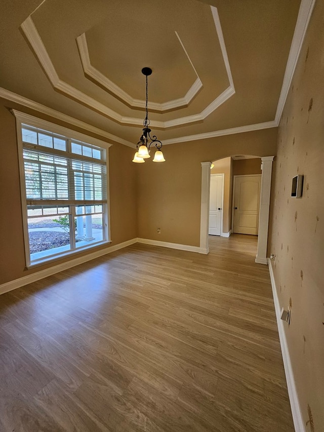 spare room with a notable chandelier, a raised ceiling, wood-type flooring, and crown molding