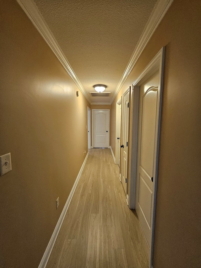 hallway featuring crown molding, a textured ceiling, and light wood-type flooring