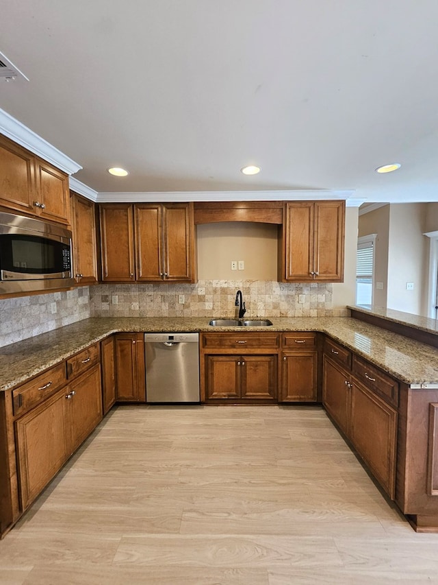 kitchen featuring sink, stainless steel appliances, kitchen peninsula, stone countertops, and light wood-type flooring