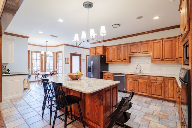 kitchen with sink, stainless steel appliances, hanging light fixtures, and a kitchen island