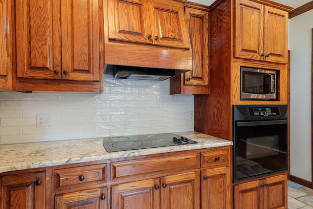 kitchen with light stone countertops, backsplash, and black appliances