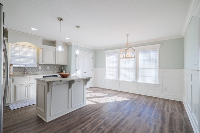 kitchen featuring a kitchen island, dark hardwood / wood-style floors, pendant lighting, a breakfast bar area, and white cabinets