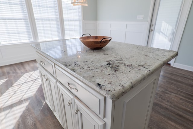 kitchen with white cabinets, a kitchen island, dark hardwood / wood-style flooring, and light stone countertops