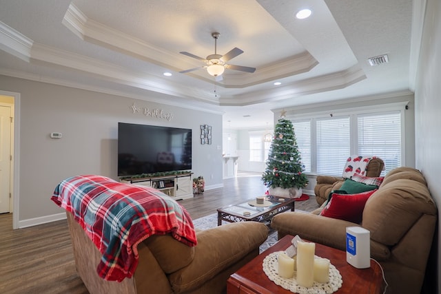 living room featuring ceiling fan, dark hardwood / wood-style flooring, crown molding, and a tray ceiling