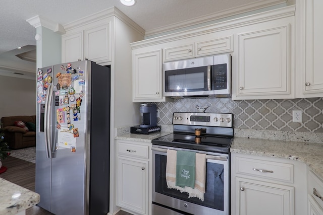 kitchen with stainless steel appliances, white cabinetry, crown molding, and light stone counters