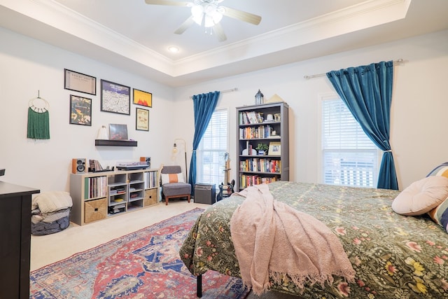 carpeted bedroom featuring ceiling fan, a raised ceiling, and multiple windows