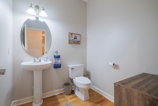 bathroom with wood-type flooring, toilet, and sink