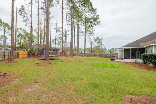 view of yard featuring a sunroom and a trampoline