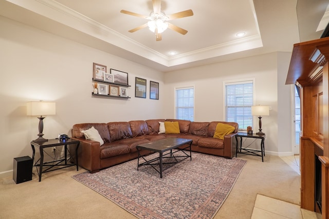 living room featuring light carpet, a raised ceiling, ceiling fan, and crown molding