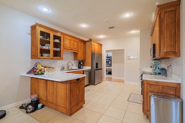 kitchen featuring sink, light tile patterned floors, appliances with stainless steel finishes, tasteful backsplash, and kitchen peninsula