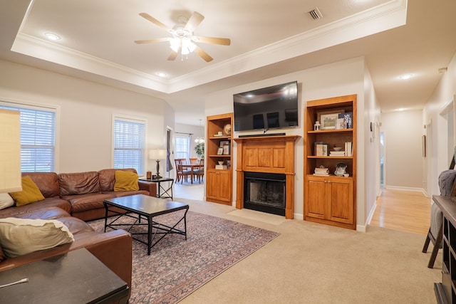 carpeted living room featuring a tray ceiling and ornamental molding