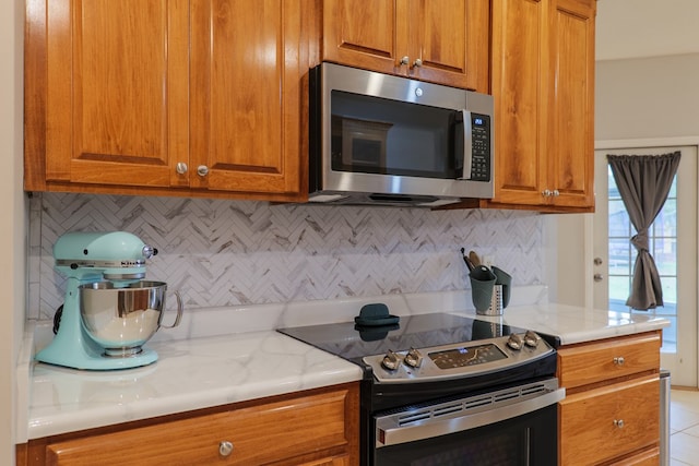 kitchen featuring light stone countertops, appliances with stainless steel finishes, and tasteful backsplash