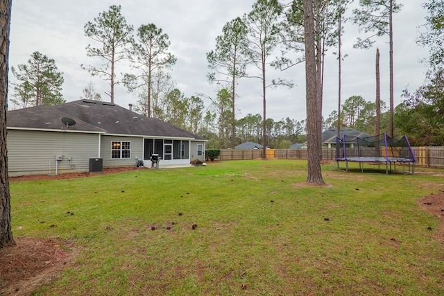 view of yard with a sunroom, a trampoline, and central AC