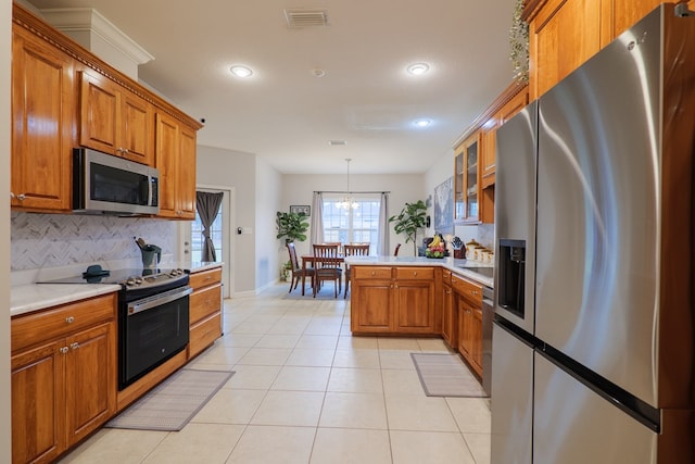 kitchen featuring tasteful backsplash, kitchen peninsula, a chandelier, decorative light fixtures, and appliances with stainless steel finishes