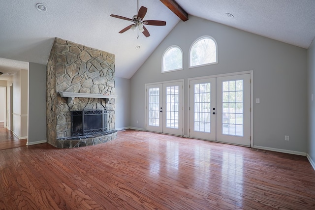 unfurnished living room featuring french doors, a fireplace, wood finished floors, and beam ceiling