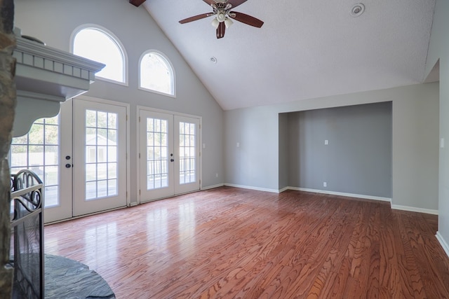 unfurnished living room featuring high vaulted ceiling, french doors, wood finished floors, and baseboards