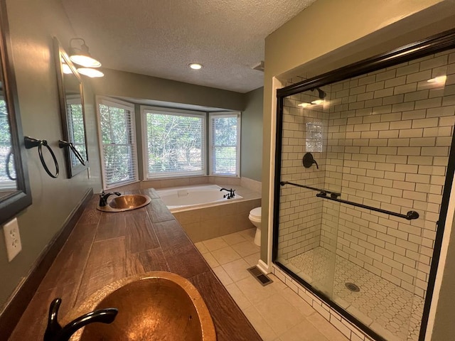 full bathroom featuring a shower stall, a textured ceiling, a sink, and tile patterned floors