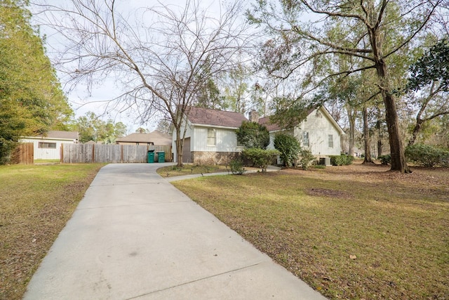 view of front of house featuring a chimney, a front yard, fence, stone siding, and driveway