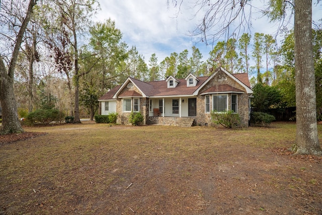 view of front of house with stone siding, a porch, and a front yard