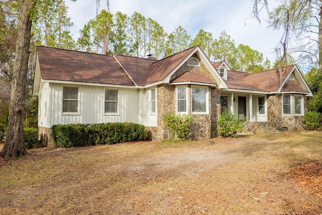 view of front of home with stone siding, a shingled roof, and board and batten siding