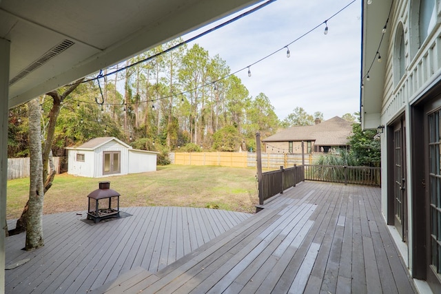 wooden terrace with a yard, a fenced backyard, and an outbuilding