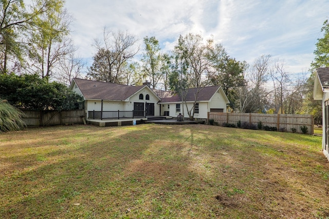 back of property with a fenced backyard, a lawn, a chimney, and a wooden deck